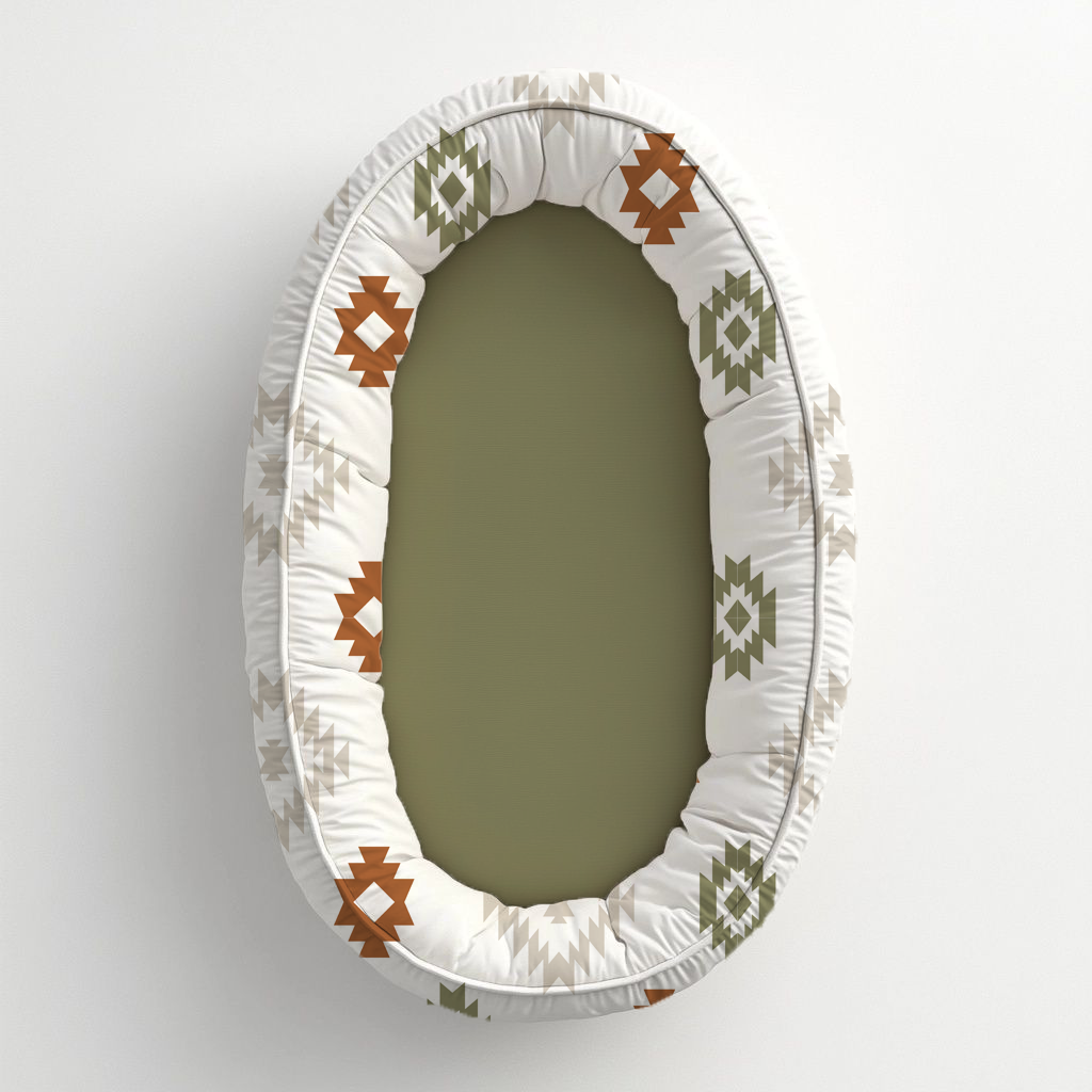 Boho themed baby nest featuring a soft olive green centre with geometric tribal-style patterns in rust, sage and neutral tones on a white padded border | Boho-tema babanes met ’n sagte olyfgroen middel en geometriese stamstyl-patrone in roes, saliegroen en neutrale kleure op ’n wit opgestopte rand.