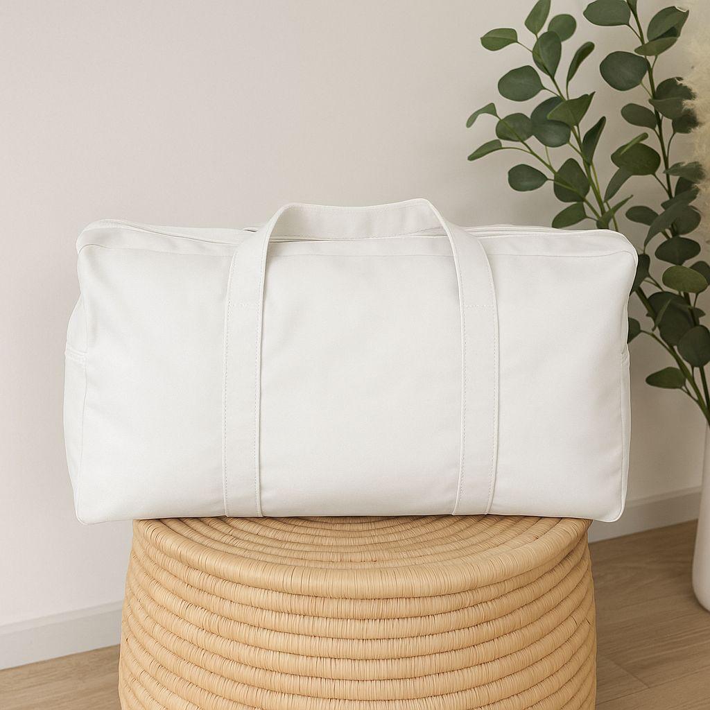 White duffel bag on a woven stool with a plant in the background