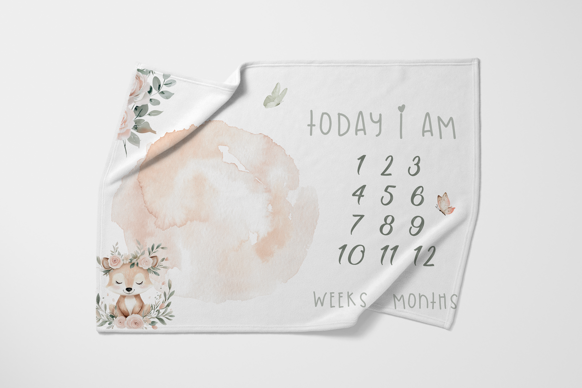Fawn & Flora baby milestone blanket featuring a sweet fawn, soft blush florals and greenery with numbers 1–12 for tracking baby’s weeks and months | Fawn & Flora baba-mylpaalkombers met ’n oulike takbok, sagte ligpienk blomme en groen blare met nommers 1–12 om baba se weke en maande vas te lê.