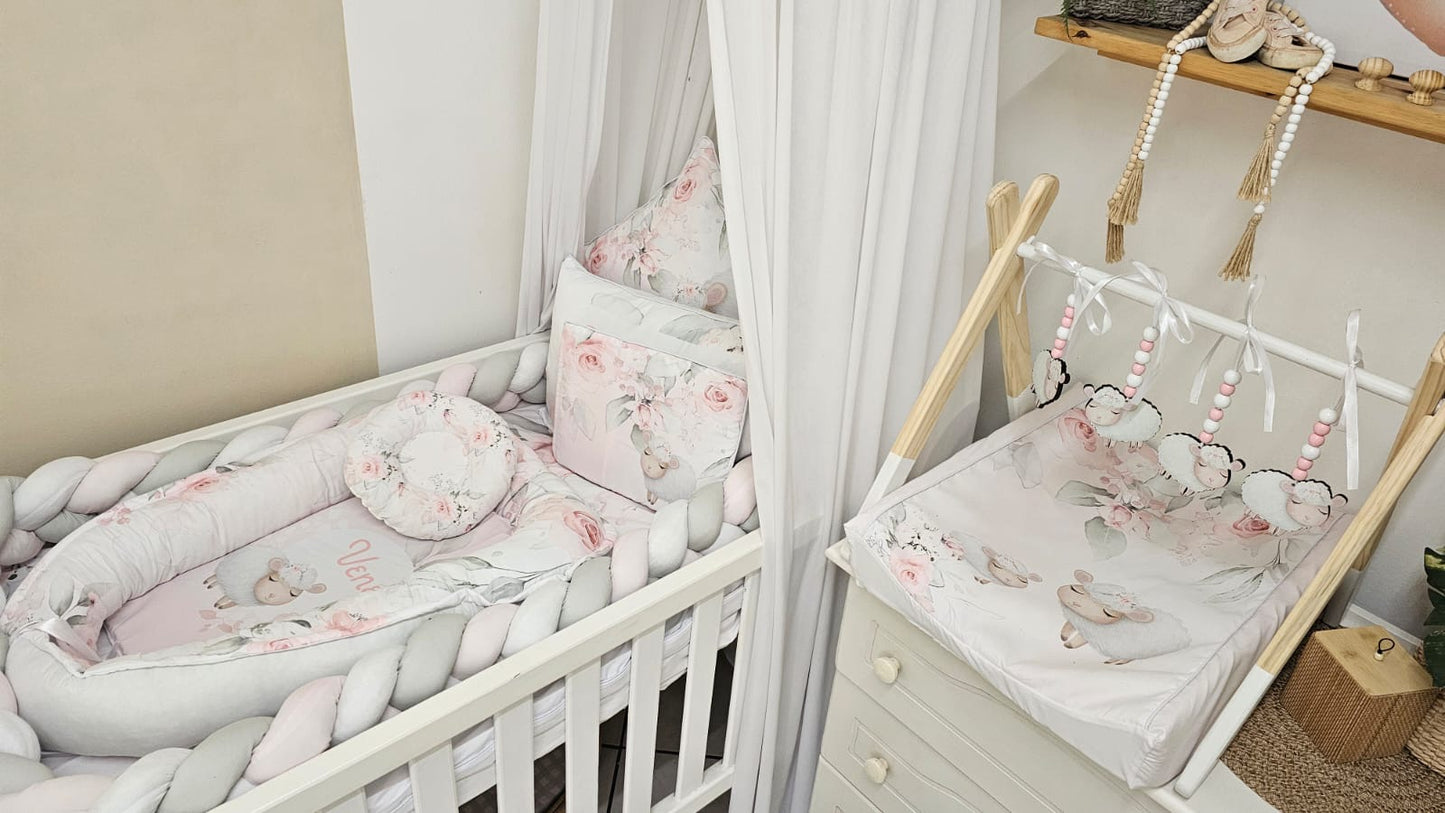 Nursery room with crib and hanging mobile, featuring floral patterns and soft colors.