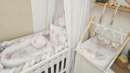 Nursery room with crib and hanging mobile, featuring floral patterns and soft colors.