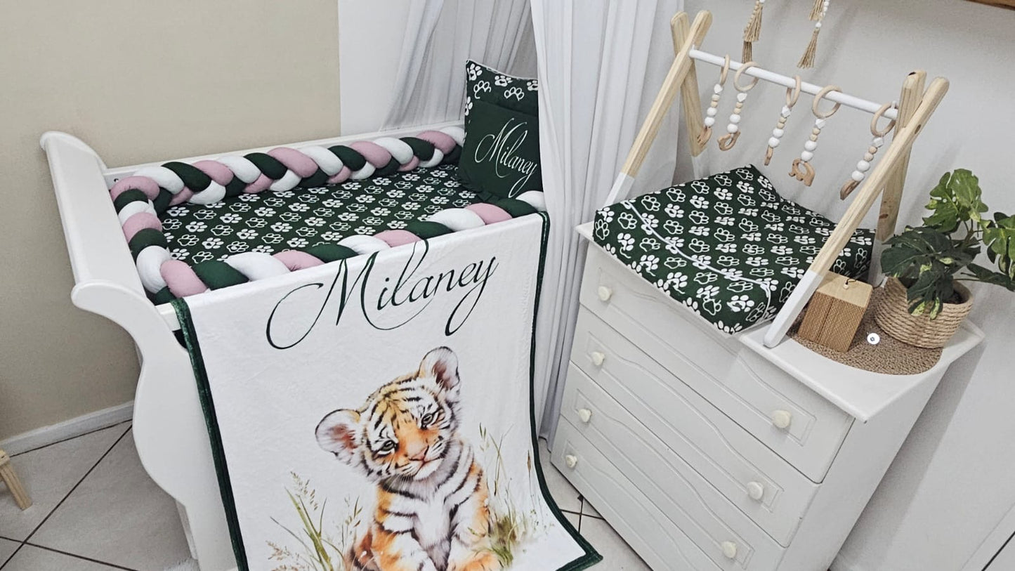 Crib with green and white bedding, featuring a tiger design, in a nursery setting.