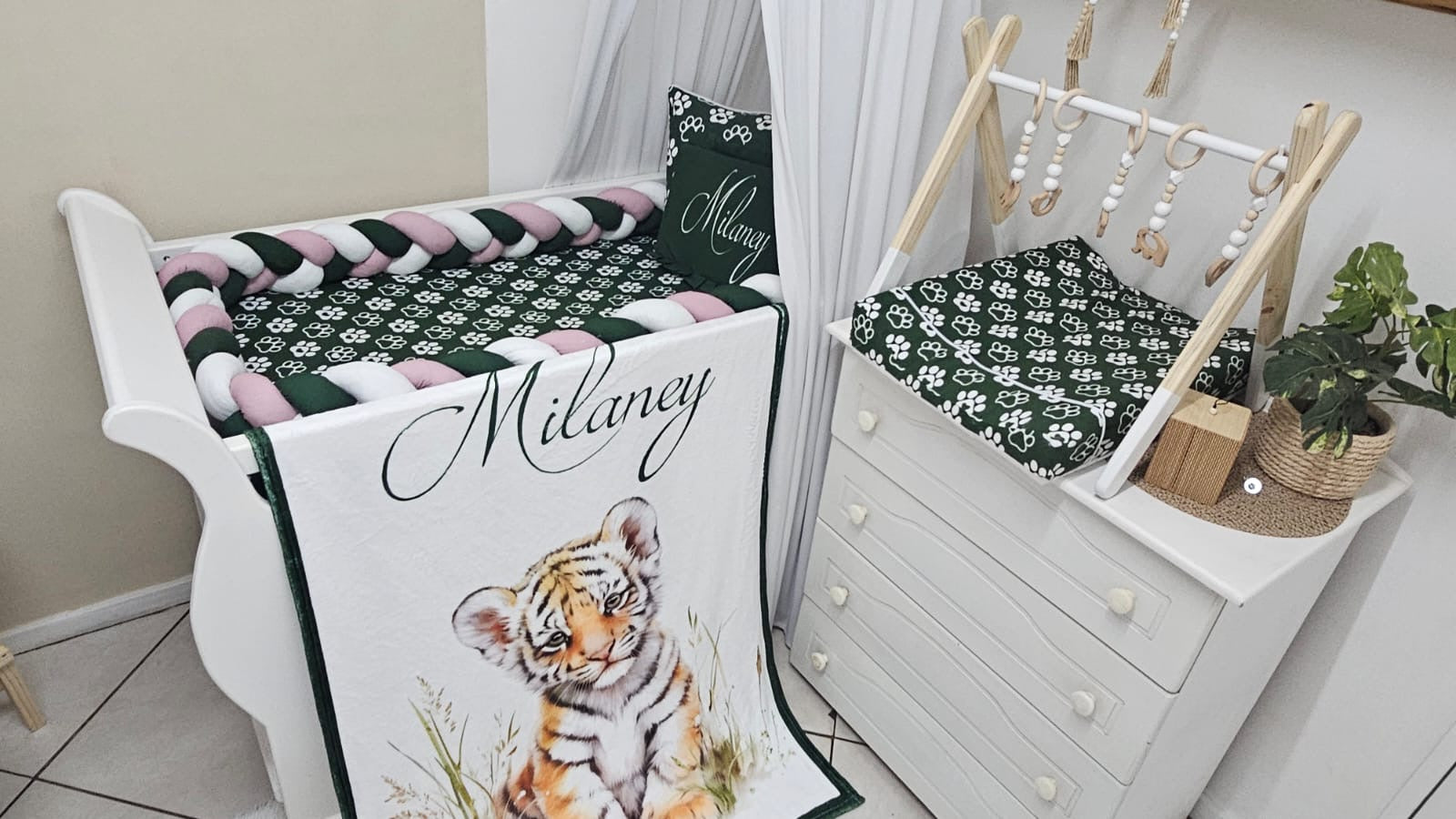 Crib with green and white bedding, featuring a tiger design, in a nursery setting.