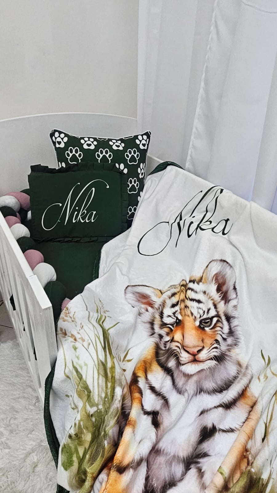 Crib with tiger-themed bedding and pillows in a nursery setting