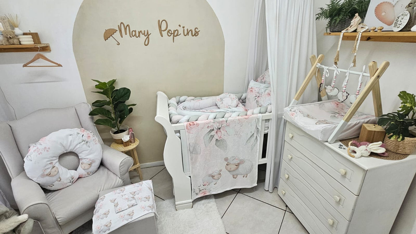 Nursery room with baby crib, chair, and changing table in a 'Mary Popins' themed room.