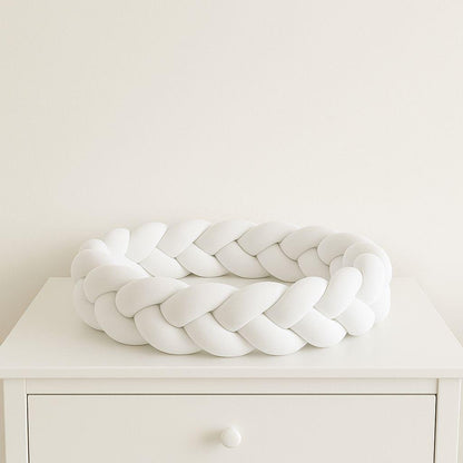 White braided decorative baby bumper  on a white surface with a plain white background