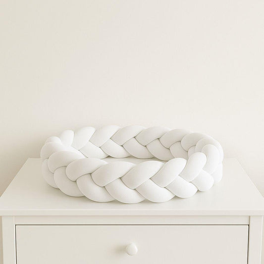 White braided decorative baby bumper  on a white surface with a plain white background