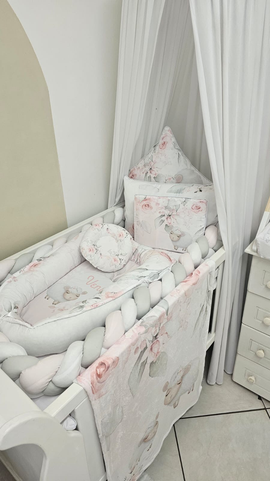 Baby crib with floral bedding and pillows in a room setting.