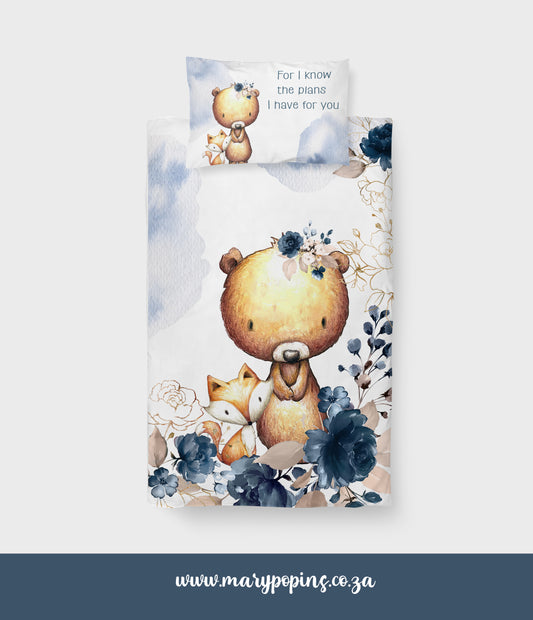 Blooming Bear big bedding featuring a sweet bear and little fox surrounded by deep blue florals, soft beige leaves and gentle blue watercolor details on a white background | Blooming Bear groot beddegoed met ’n oulike beer en klein jakkalsie omring deur diepblou blomme, sagte beige blare en ligblou waterverf-detail op ’n wit agtergrond.