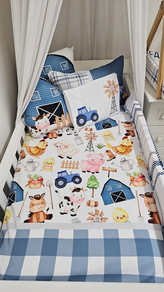 Blue Vintage Farm Life nursery cot linen featuring sweet farm animals, a blue tractor, barn, windmill, vegetables and blue gingham detailing | Blou Vintage Plaaslewe bababed-linne met oulike plaasdiere, ’n blou trekker, skuur, windpomp, groente en blou gingham-detail.