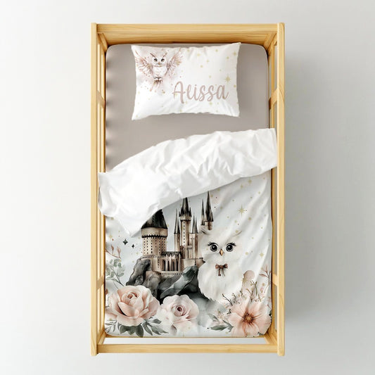 Blush Harry Potter cot duvet cover featuring a magical castle, sweet white owl, soft blush florals and delicate golden star details on a white background | Blush Harry Potter bababed-duvetoortreksel met ’n magiese kasteel, oulike wit uil, sagte ligpienk blomme en delikate goue sterdetail op ’n wit agtergrond.