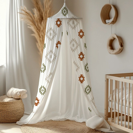 Boho themed nursery canopy featuring geometric tribal-style patterns in rust, olive green and soft neutral tones on flowing white fabric, styled beside a natural wood cot | Boho-tema kinderkamer-bedhemel met geometriese stamstyl-patrone in roes, olyfgroen en sagte neutrale kleure op vloeiende wit materiaal, gestileer langs ’n natuurlike hout bababed.