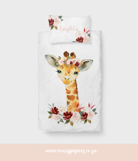 Bold Giraffe big bedding featuring a sweet giraffe wearing a floral crown, surrounded by burgundy, blush and cream flowers with soft green foliage on a white background | Bold Giraffe groot beddegoed met ’n oulike kameelperd met ’n blomkroon, omring deur wynrooi, ligpienk en roomkleurige blomme met sagte groen blare op ’n wit agtergrond.
