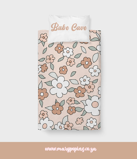 Daisy Babe big bedding featuring a retro floral print with white, peach and terracotta flowers, soft sage leaves and a warm blush background | Daisy Babe groot beddegoed met ’n retro blompatroon van wit, perske- en terrakottablomme, sagte saliegroen blare en ’n warm ligpienk agtergrond.