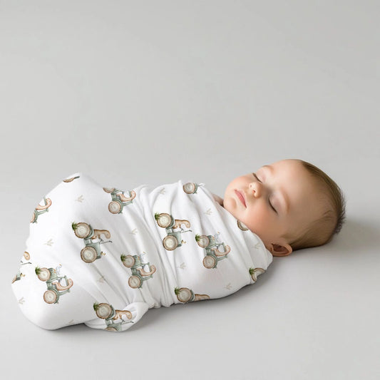 Dino Tails baby swaddle set featuring sweet little dinosaurs in soft sage, beige and neutral tones on a clean white background | Dino Tails baba-inbakerstel met oulike klein dinosourusse in sagte saliegroen, beige en neutrale kleure op ’n skoon wit agtergrond.