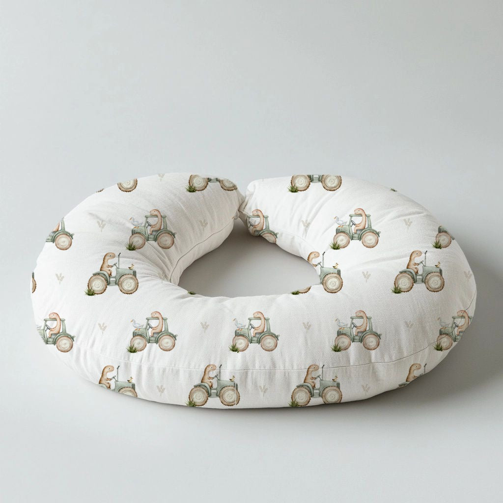 Dino Tractor Tails nursing pillow featuring sweet little dinosaurs riding vintage-style tractors in soft sage, beige and neutral tones on a white background | Dino Tractor Tails voedingskussing met oulike klein dinosourusse wat op klassieke trekkers ry in sagte saliegroen, beige en neutrale kleure op ’n wit agtergrond.
