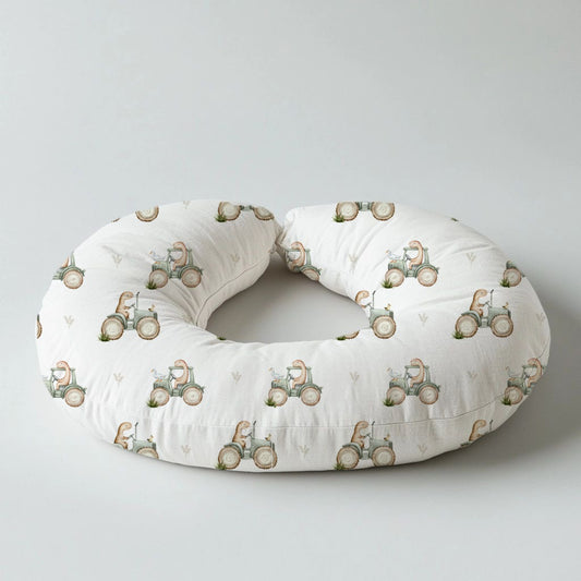 Dino Tractor Tails nursing pillow featuring sweet little dinosaurs riding vintage-style tractors in soft sage, beige and neutral tones on a white background | Dino Tractor Tails voedingskussing met oulike klein dinosourusse wat op klassieke trekkers ry in sagte saliegroen, beige en neutrale kleure op ’n wit agtergrond.