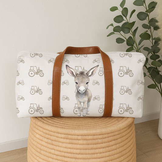 Donkey Dreams hospital bag featuring a sweet grey donkey with a soft neutral tractor pattern and tan handles, perfect for baby essentials | Donkey Dreams hospitaaltas met ’n oulike grys donkie, sagte neutrale trekkerpatroon en bruin handvatsels, perfek vir baba-benodigdhede.