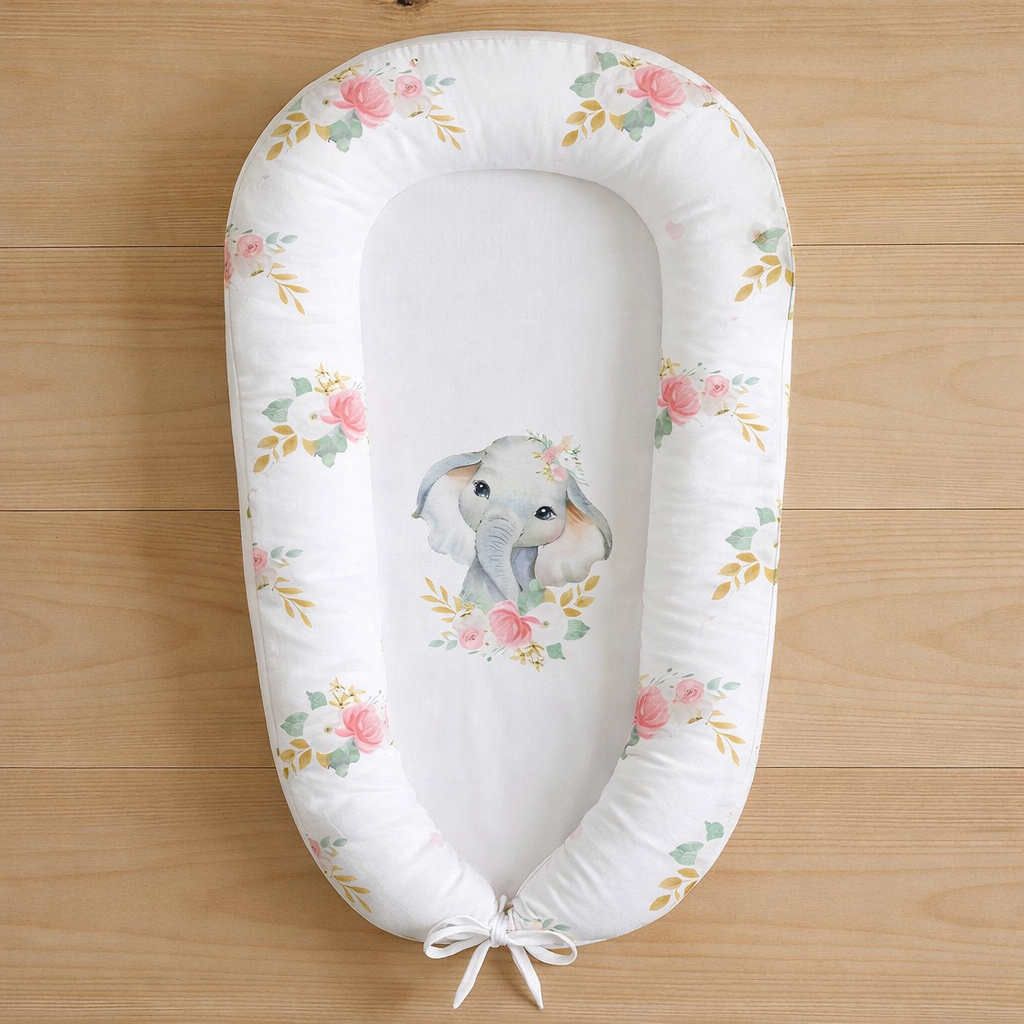 Ellie Floral baby nest featuring watercolour elephant and soft pink floral design, photographed flat lay on wooden surface