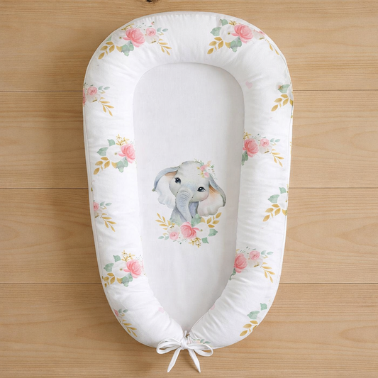 Ellie Floral baby nest featuring watercolour elephant and soft pink floral design, photographed flat lay on wooden surface