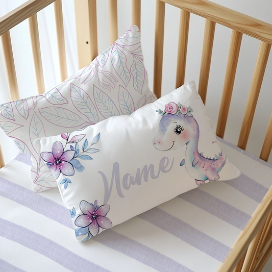Girly Dino personalised nursery pillow featuring a sweet pastel purple dinosaur with a pink floral crown, soft purple and blue flowers, and the name “Mane” | Girly Dino gepersonaliseerde kinderkamer-kussing met ’n oulike pastelpers dinosourus met ’n pienk blomkroon, sagte pers en blou blomme, en die naam “Mane”.