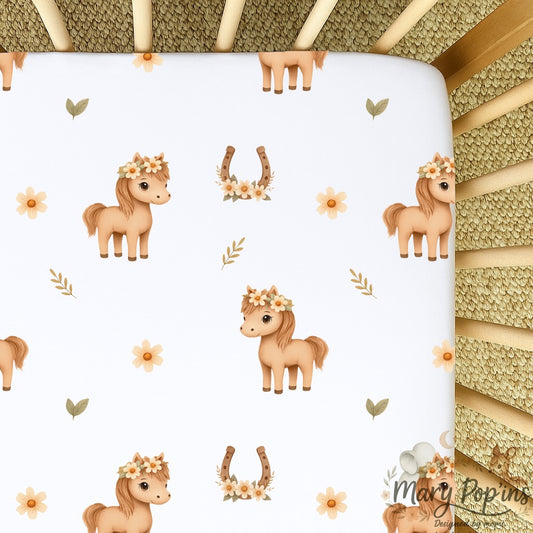 Horsey Blossom cot sheet featuring sweet little horses with floral crowns, horseshoes, daisies and delicate leafy details on a white background | Horsey Blossom bababed-laken met oulike perdjies met blomkrone, hoefysters, madeliefies en fyn blaardetail op ’n wit agtergrond.