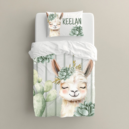 Neutral Succulents Llama big bedding featuring a sweet smiling llama with a soft sage succulent crown, cactus details, pale green stripes and the personalised name “Keelan” | Neutrale Vetplante Lama groot beddegoed met ’n oulike glimlaggende lama, ’n sagte saliegroen vetplantkroon, kaktusdetail, liggroen strepe en die gepersonaliseerde naam “Keelan”.