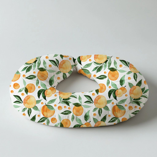 Peachy Goose nursing pillow featuring a fresh peach and green leaf print on a white background, designed for comfortable baby feeding and support | Peachy Goose voedingskussing met ’n vars perske- en groen blaarpatroon op ’n wit agtergrond, ontwerp vir gemaklike babavoeding en ondersteuning.