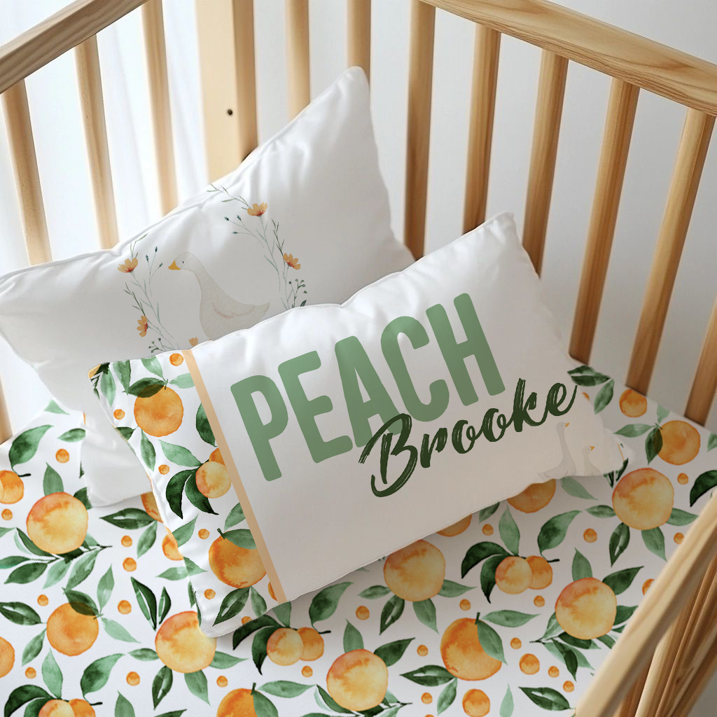 Peachy Goose nursery pillow set featuring a personalised “Peach Brooke” cushion, soft goose illustration and matching peach and green leaf prints | Peachy Goose kinderkamer-kussingstel met ’n gepersonaliseerde “Peach Brooke”-kussing, sagte gansillustrasie en bypassende perske- en groen blaarpatrone.