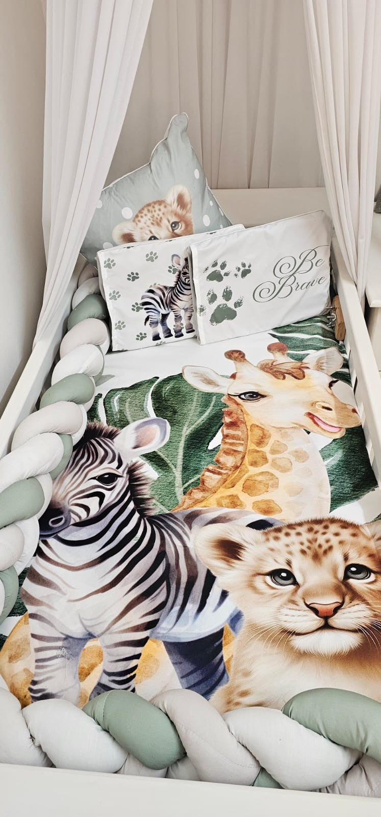 Safari Friends cot bedding set featuring a baby nest, braided cot bumper and matching cushions with a zebra, giraffe and lion cub in soft sage, white and neutral tones | Safari Vriende bababeddegoedstel met ’n babanes, gevlegte bababedbuffer en bypassende kussings met ’n sebra, kameelperd en leeuwelpie in sagte saliegroen, wit en neutrale kleure.