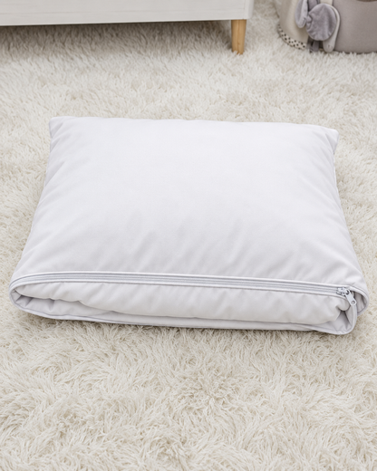 A folded white pillowcase or pillow cover with a zipper closure, resting on a fluffy white shag rug.
