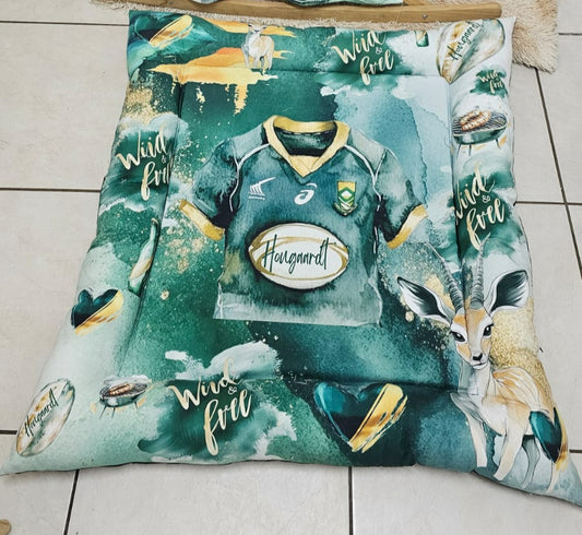 Springbok rugby playmat featuring a green and gold South African rugby design with a Springbok, rugby jersey, rugby balls and “Wild & Free” details | Springbok rugby-speelmat met ’n groen-en-goue Suid-Afrikaanse rugby-ontwerp met ’n springbok, rugbytrui, rugbyballe en “Wild & Free”-besonderhede.