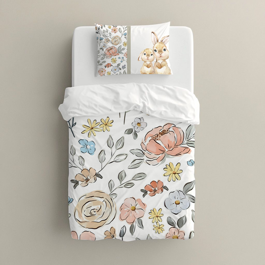 Subtle Blooms big bedding featuring delicate blush, peach, cream, yellow and soft blue flowers with fine grey-green leaves on a clean white background | Subtiele Blomme groot beddegoed met delikate ligpienk, perske-, room-, geel en sagte blou blomme met fyn grysgroen blare op ’n skoon wit agtergrond.