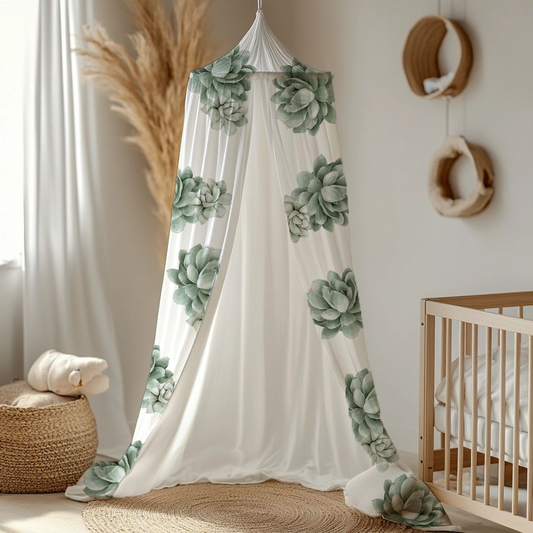 Succulents cot canopy featuring soft sage green succulent prints on flowing white fabric, styled beside a natural wood cot in a calm neutral nursery | Vetplante bababedhemel met sagte saliegroen vetplant-afdrukke op vloeiende wit materiaal, gestileer langs ’n natuurlike hout bababed in ’n rustige neutrale kinderkamer.