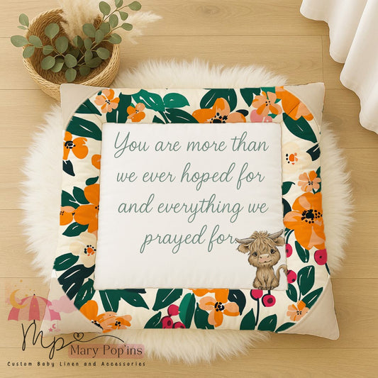 Tropical Floral Highlands baby playmat featuring a colourful orange, pink and green floral border, a sweet Highland cow and the quote “You are more than we ever hoped for and everything we prayed for” | Tropical Floral Highlands baba-speelmat met ’n kleurvolle oranje, pienk en groen blomrand, ’n oulike Highland-bees en die aanhaling “You are more than we ever hoped for and everything we prayed for”.