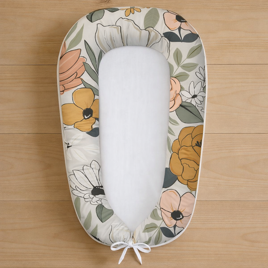 Vintage Poppy baby nest featuring large mustard, peach and white floral design, photographed flat lay on wooden surface
