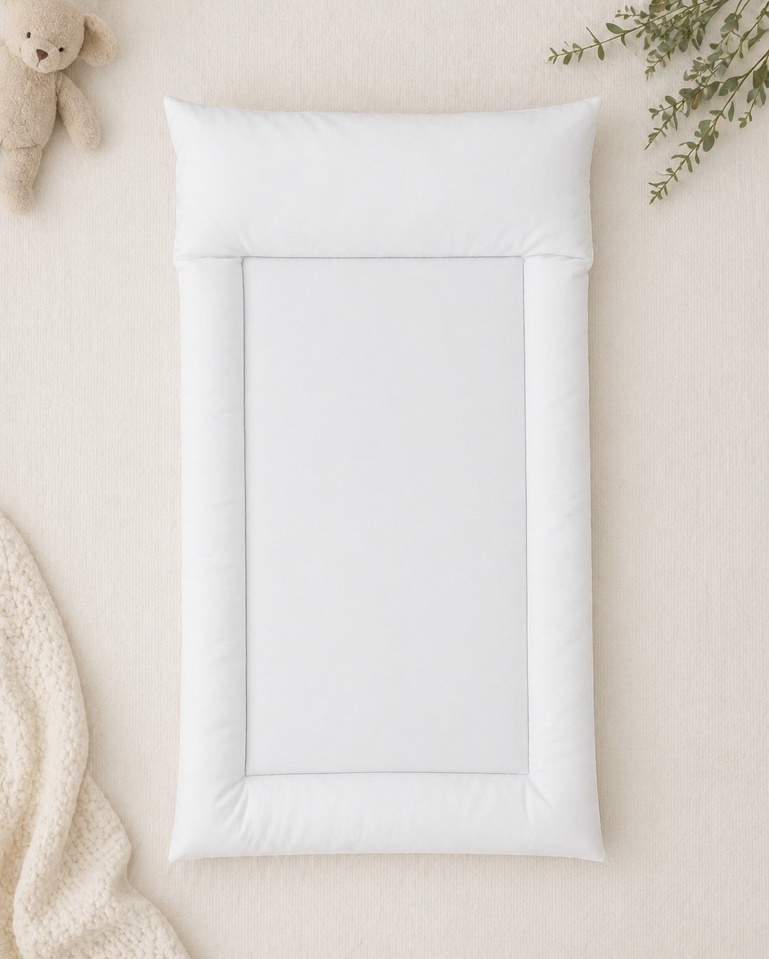 Soft white padded baby changing mat with raised cushioned sides, designed for comfortable nappy changes and everyday baby care | Sagte wit opgestopte baba-versorgingsmat met verhoogde sagte kante, ontwerp vir gemaklike doekruil en alledaagse babaversorging.