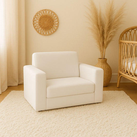 Soft white toddler couch with wide armrests and a cushioned seat, styled in a neutral nursery or children’s room | Sagte wit kleuterbank met breë armleunings en ’n gemaklike kussingsitplek, gestileer in ’n neutrale baba- of kinderkamer.